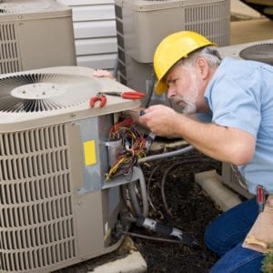 An HVAC contractor working on an A/C unit