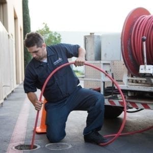 Plumber using hydrojetting to unclog a pipe